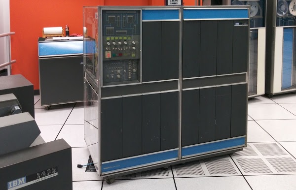 An IBM 1401 mainframe computer at the Computer History Museum. Behind it is the IBM 1406 Storage Unit, providing an additional 12,000 characters of storage. IBM 729 tape drives are at the right and an IBM 1402 Card Read Punch is at the far left.